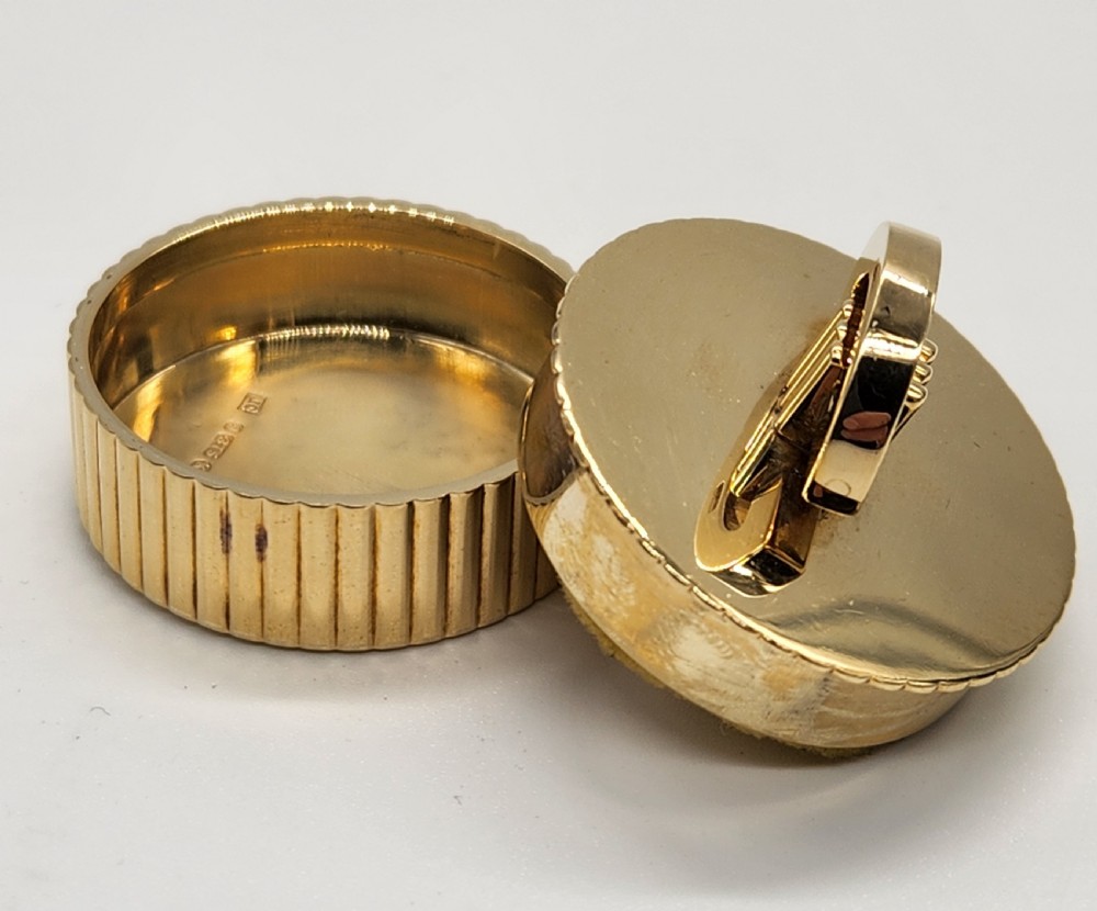 A circular polished yellow gold box featuring vertical fluted sides and a hinged semicircular handle with visible hallmarks. View IV