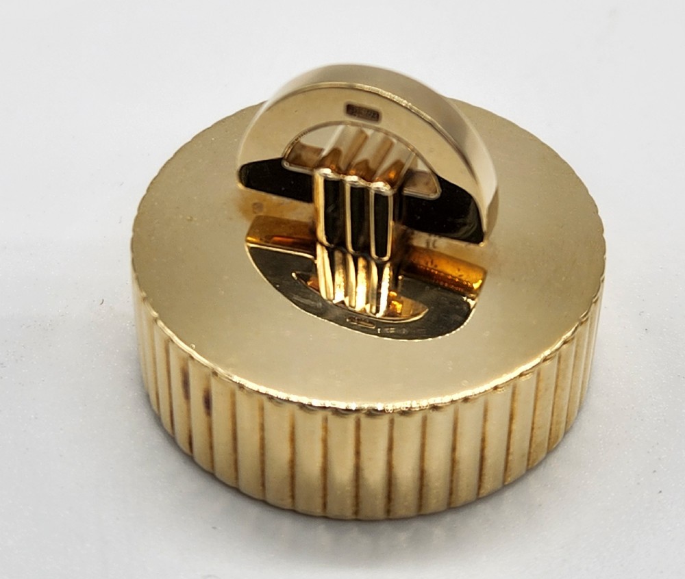 A circular polished yellow gold box featuring vertical fluted sides and a hinged semicircular handle with visible hallmarks. View V
