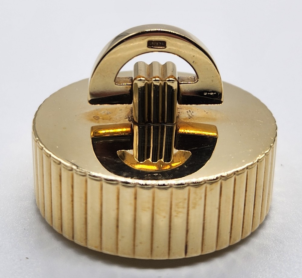 A circular polished yellow gold box featuring vertical fluted sides and a hinged semicircular handle with visible hallmarks. View VII