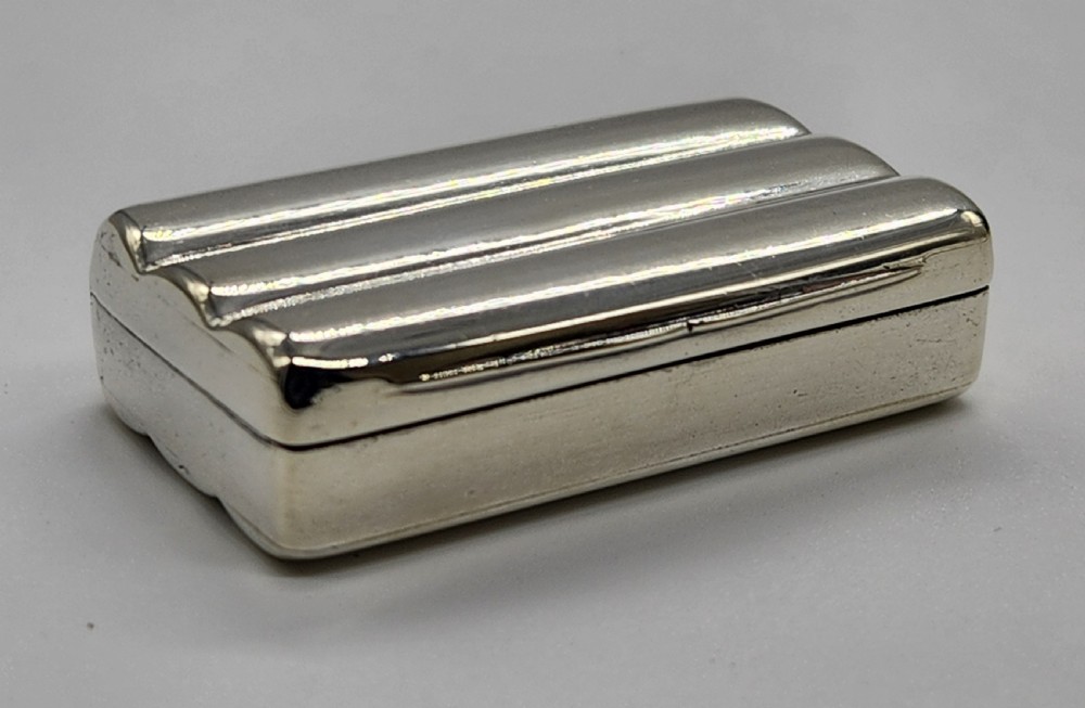 A small rectangular Georgian sterling silver snuff box featuring fluted channels on the cover and a polished silver finish. View II