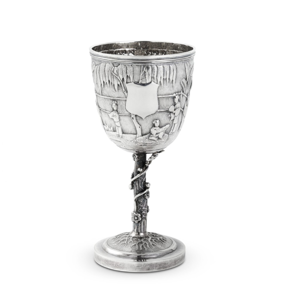 A late 19th-century Chinese export silver goblet featuring repousse relief depicting architectural structures and figures, supported by a textured prunus stem on a circular base. View IV