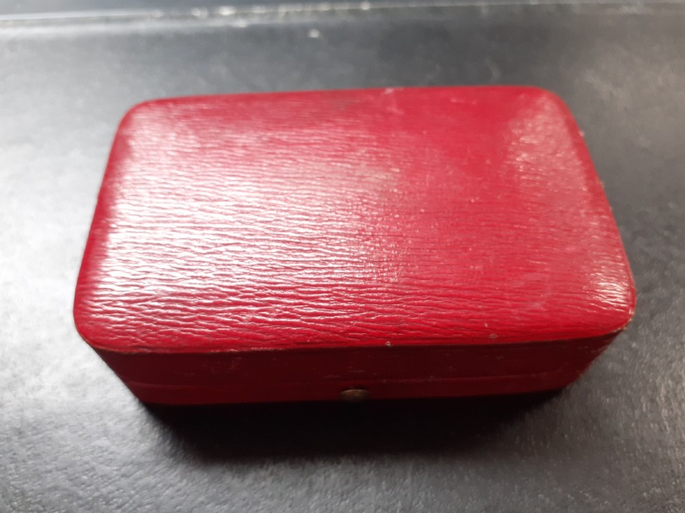 A rectangular 18 carat gold snuff box featuring engine-turned panels surrounded by a chased foliate border. View X
