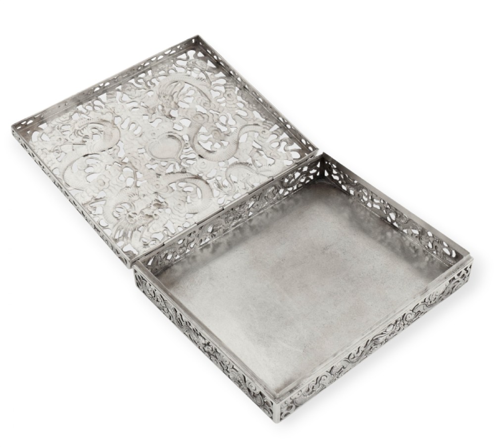 A rectangular silver box featuring detailed pierced openwork of two dragons amidst clouds around a central pearl. View V