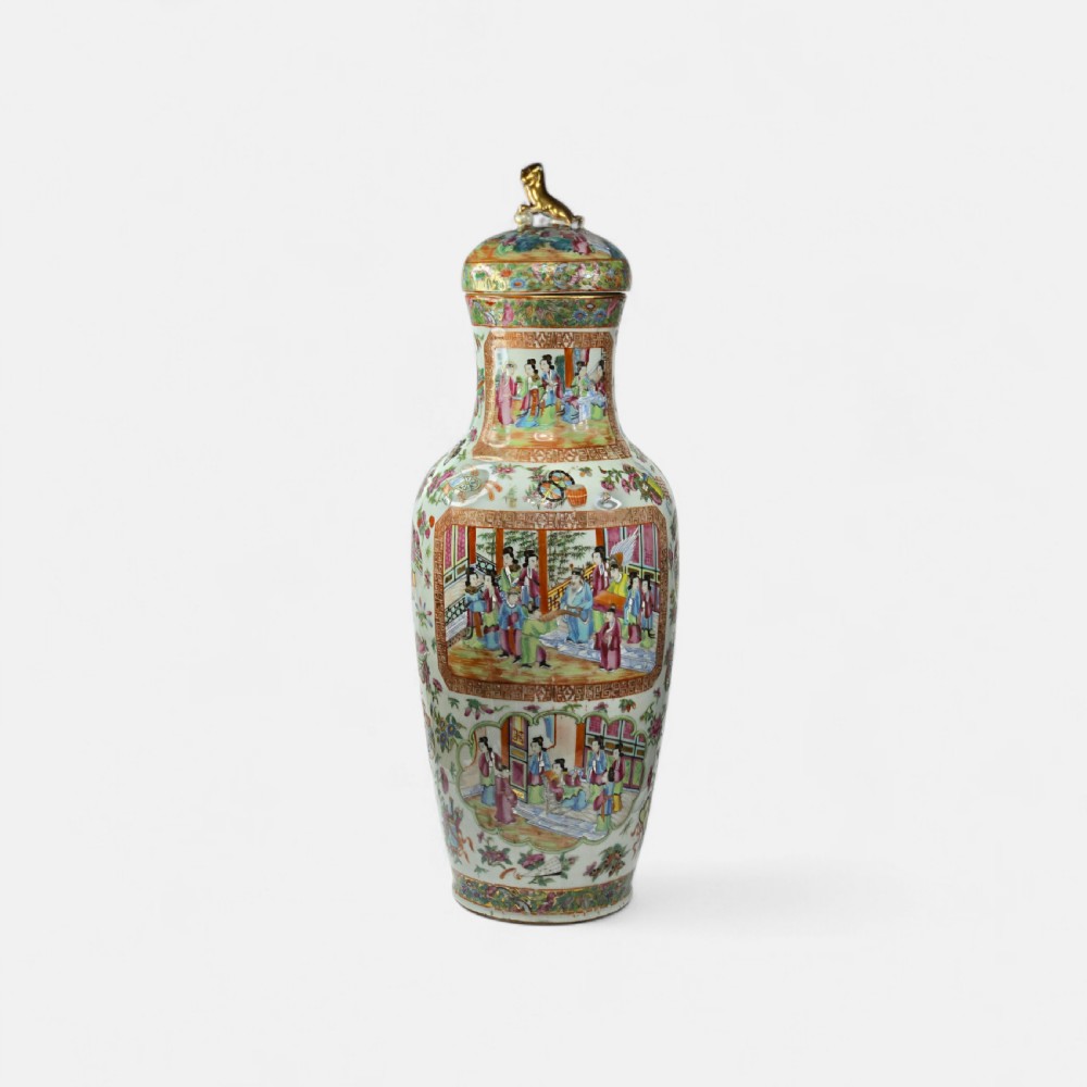 A 19th-century Cantonese Rose Mandarin porcelain baluster vase decorated with narrative figure panels, floral enamel borders, and a domed cover topped with a gilt foo dog finial. View II