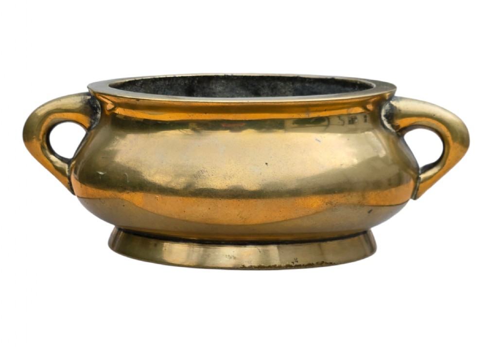 An 18th-century Chinese bronze censer featuring a rounded bombe body, flared rim, splayed foot ring, and two loop handles.