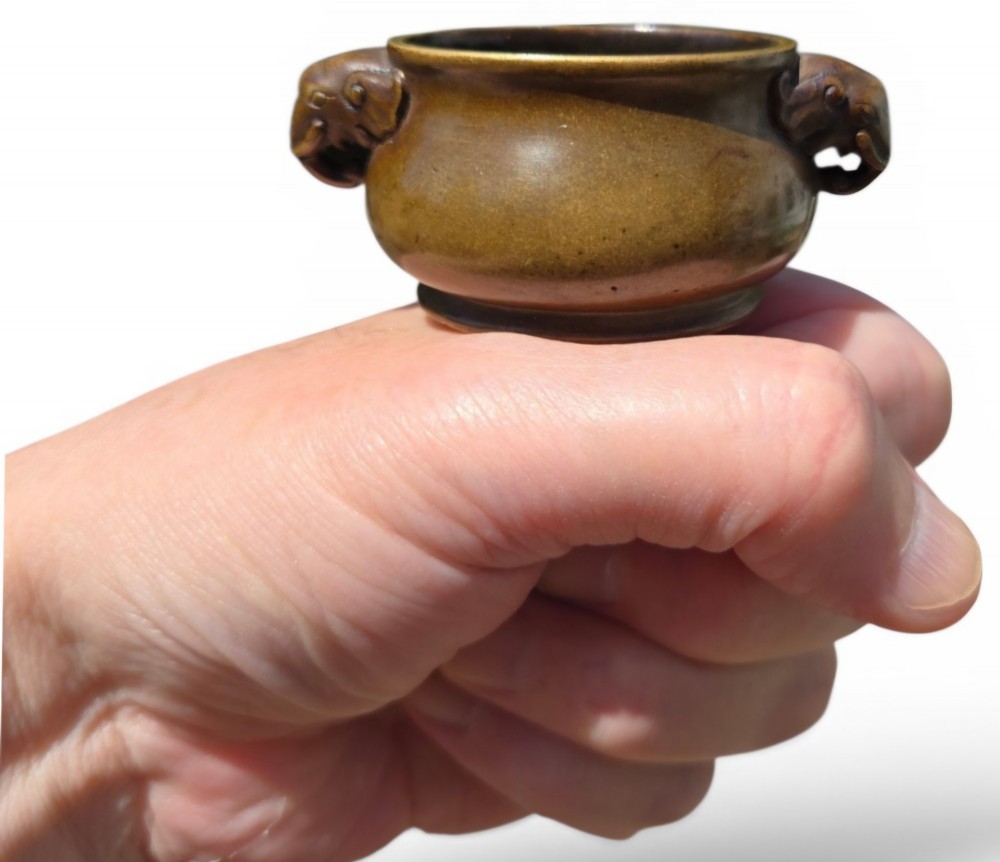 A miniature dark bronze censer featuring a rounded body, twin elephant head handles with curved trunks, and a circular raised footring. View XV