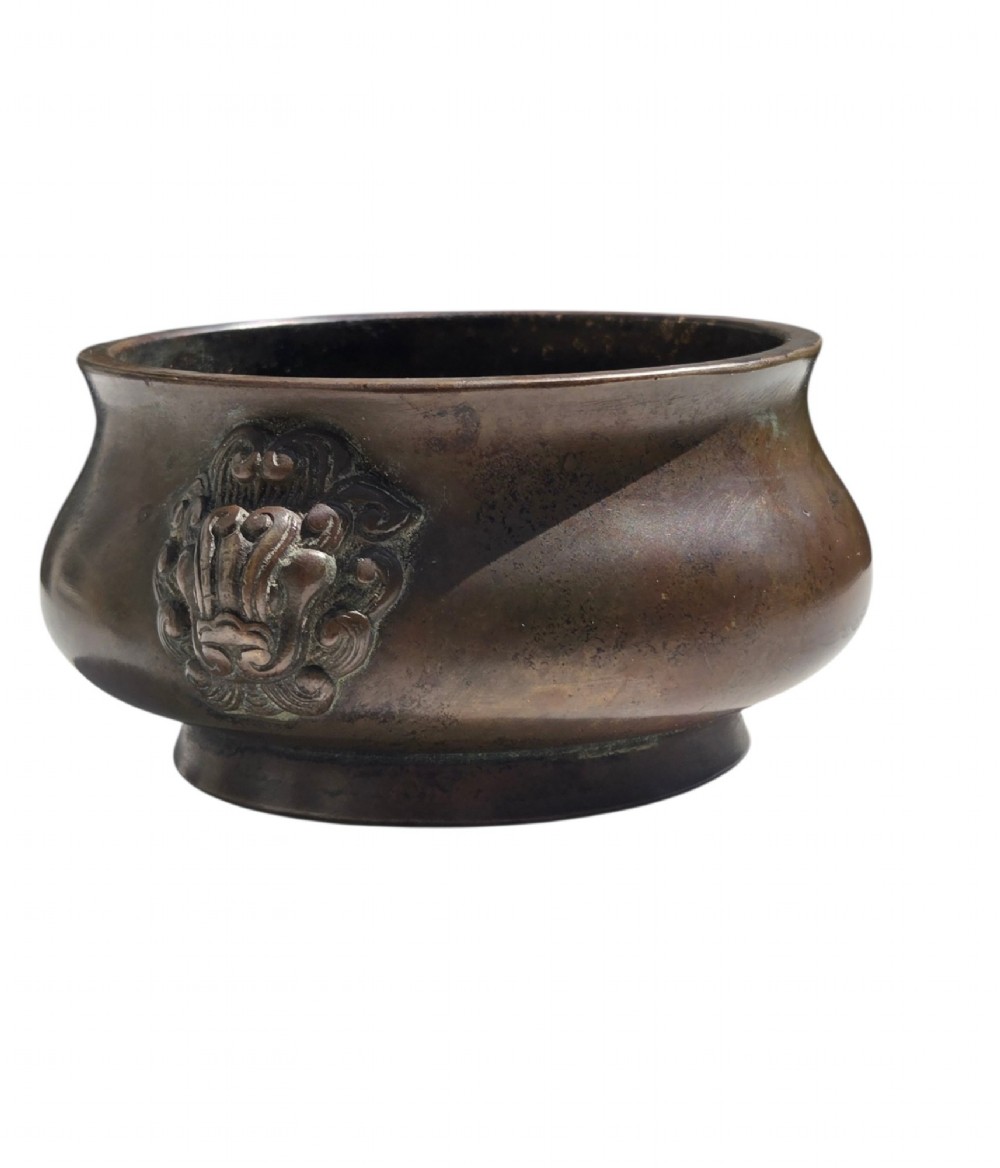 A cast bronze censer featuring a flared rim, compressed globular body, low circular foot, and cast relief taotie mask handles on the side. View III