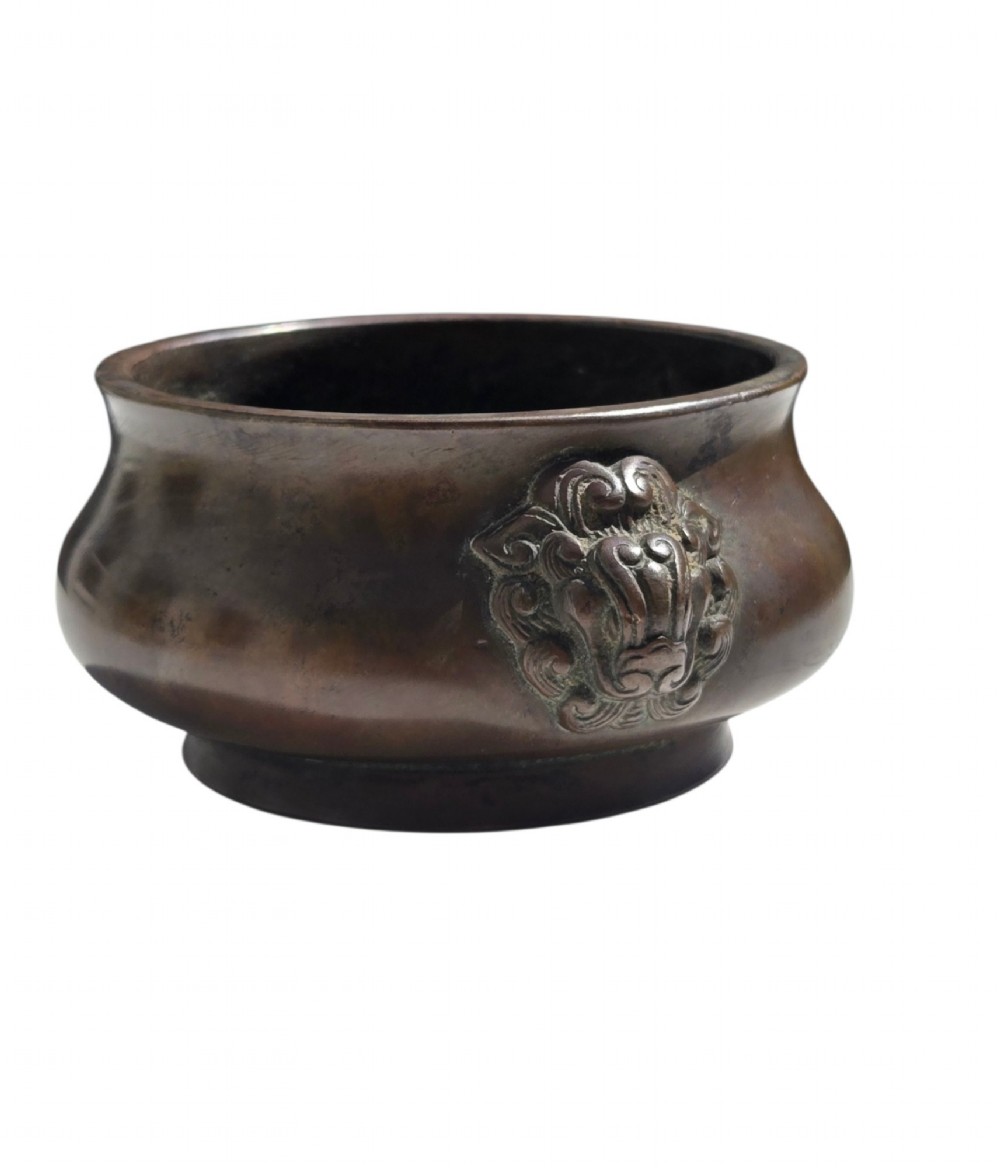 A cast bronze censer featuring a flared rim, compressed globular body, low circular foot, and cast relief taotie mask handles on the side. View V