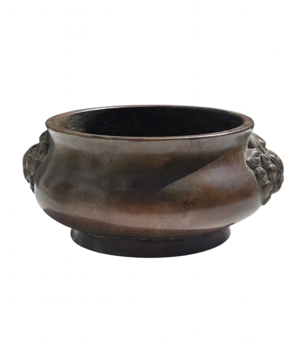 A cast bronze censer featuring a flared rim, compressed globular body, low circular foot, and cast relief taotie mask handles on the side. View VI
