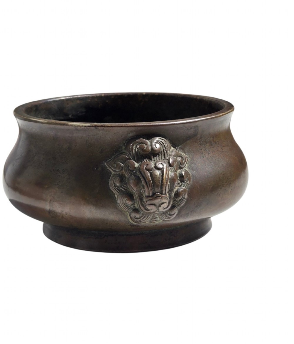 A cast bronze censer featuring a flared rim, compressed globular body, low circular foot, and cast relief taotie mask handles on the side. View VII