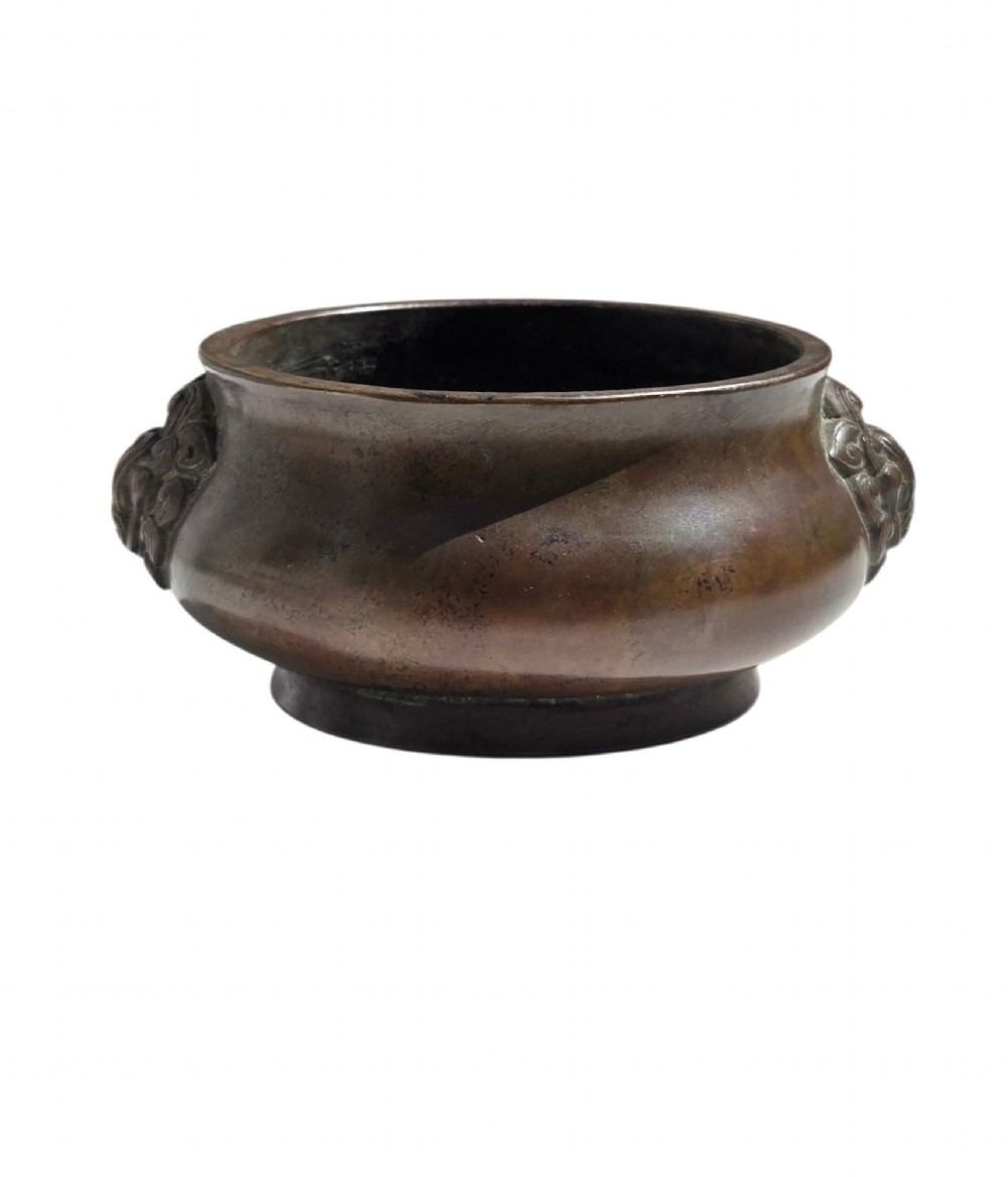 A cast bronze censer featuring a flared rim, compressed globular body, low circular foot, and cast relief taotie mask handles on the side. View VIII