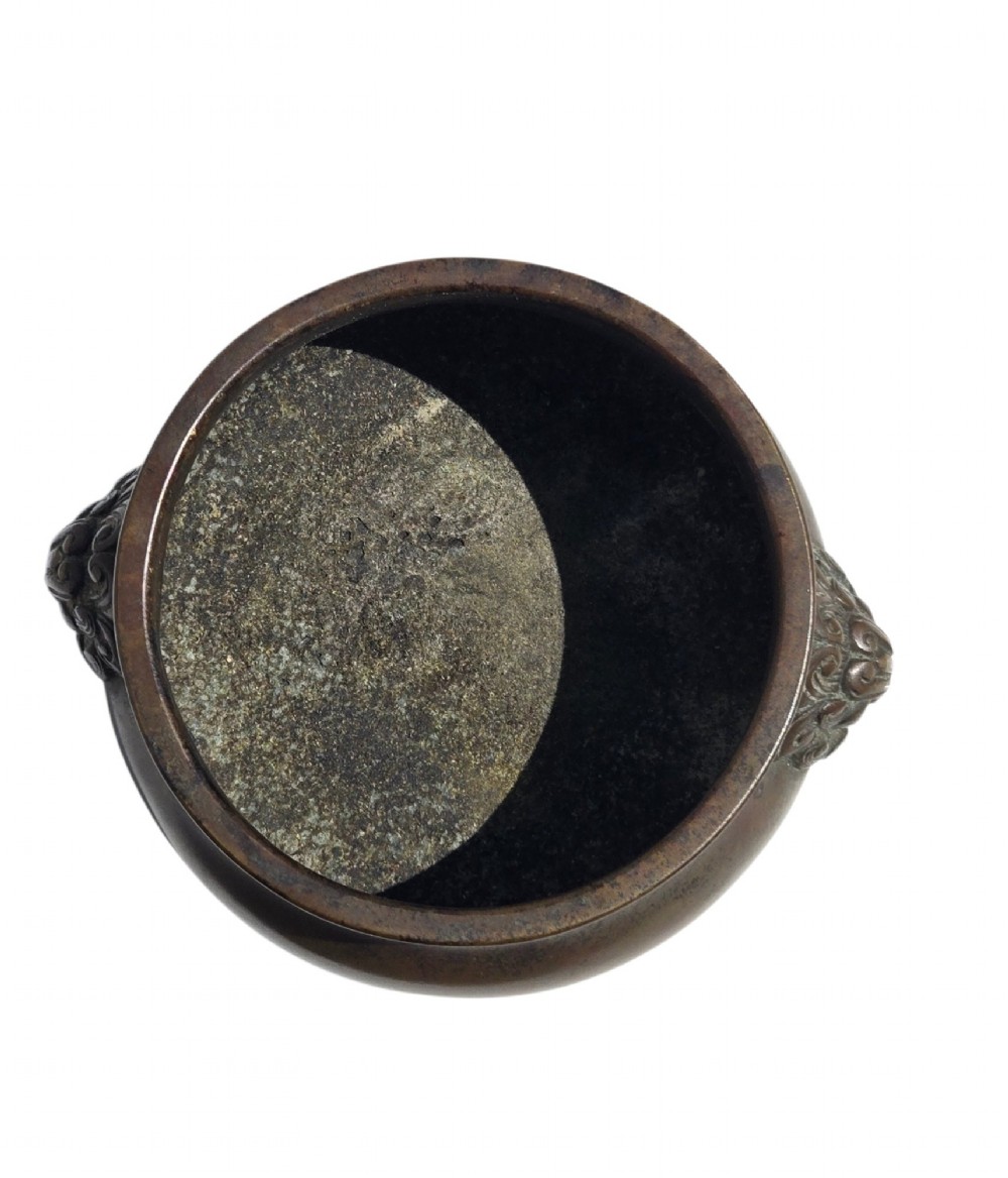 A cast bronze censer featuring a flared rim, compressed globular body, low circular foot, and cast relief taotie mask handles on the side. View XIII