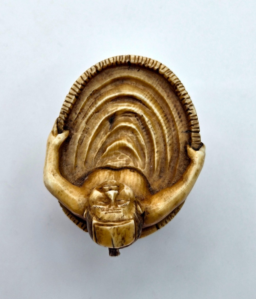 A small carved stag antler netsuke depicting a man sitting inside a wooden bath tub with carved water ripples. View IV