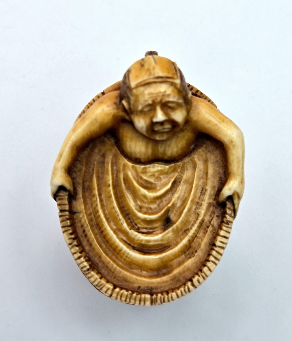 A small carved stag antler netsuke depicting a man sitting inside a wooden bath tub with carved water ripples. View V
