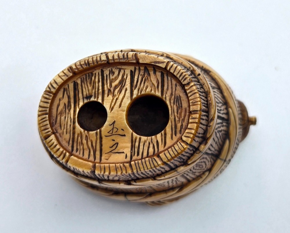 A small carved stag antler netsuke depicting a man sitting inside a wooden bath tub with carved water ripples. View VI