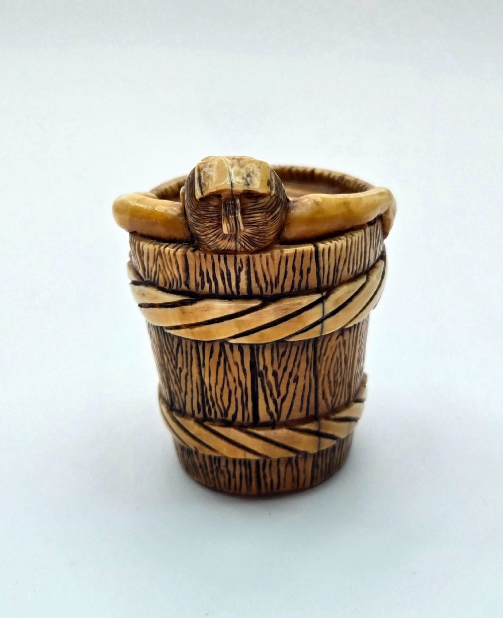 A small carved stag antler netsuke depicting a man sitting inside a wooden bath tub with carved water ripples. View VIII
