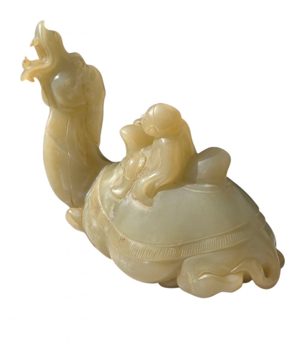 A carved pale green bowenite serpentine sculpture depicting a camel with its head raised, carrying a seated rider figure. View II