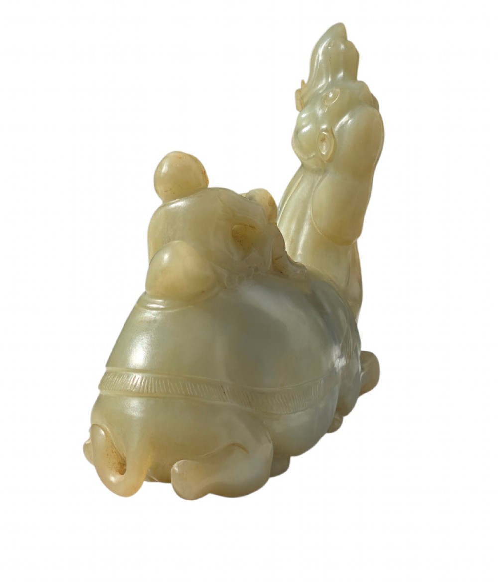 A carved pale green bowenite serpentine sculpture depicting a camel with its head raised, carrying a seated rider figure. View III