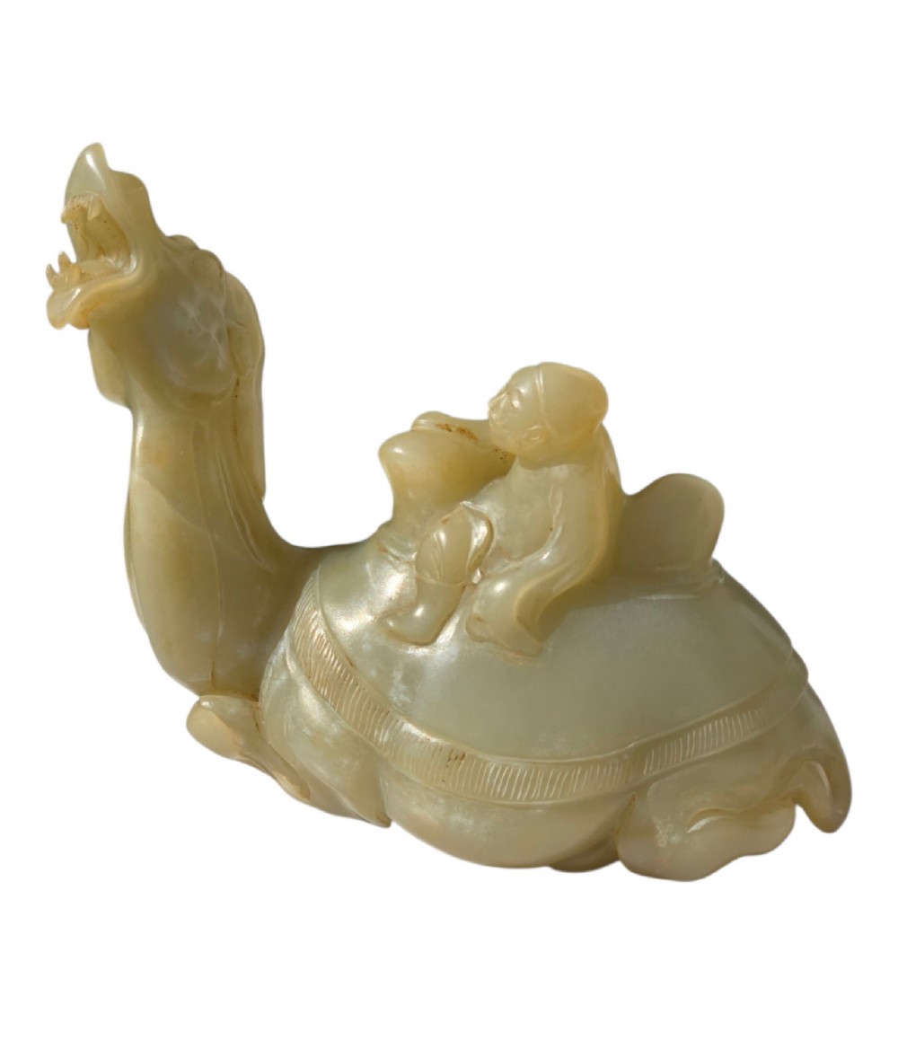 A carved pale green bowenite serpentine sculpture depicting a camel with its head raised, carrying a seated rider figure. View VI