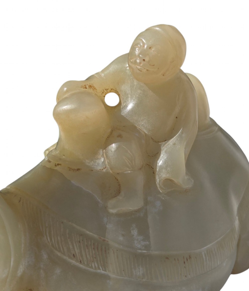A carved pale green bowenite serpentine sculpture depicting a camel with its head raised, carrying a seated rider figure. View IX