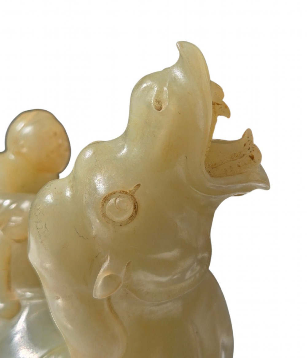 A carved pale green bowenite serpentine sculpture depicting a camel with its head raised, carrying a seated rider figure. View XII