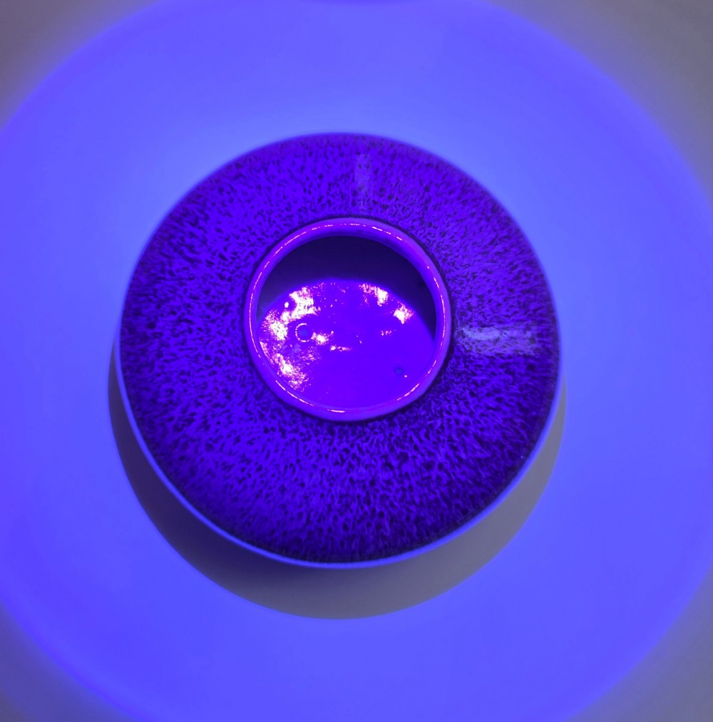 A compressed circular Chinese porcelain brush washer featuring a mottled purple and lavender blue flambe glaze. View X