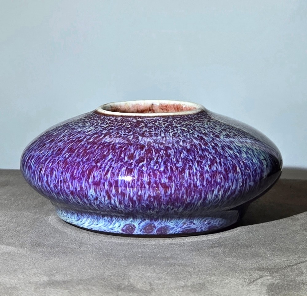 A compressed circular Chinese porcelain brush washer featuring a mottled purple and lavender blue flambe glaze. View XI