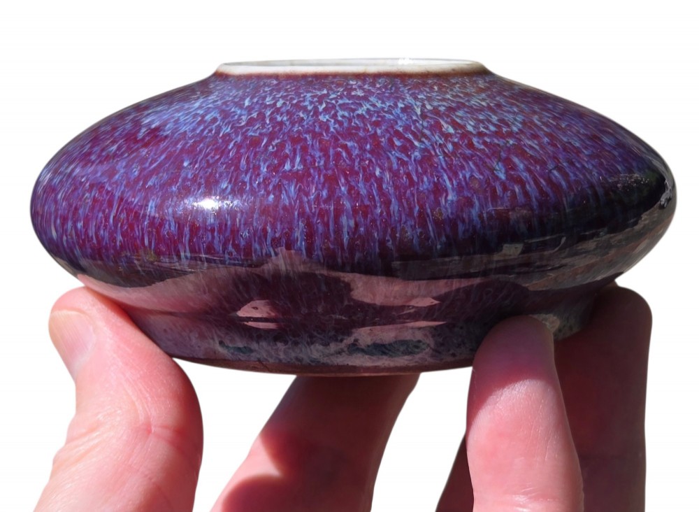 A compressed circular Chinese porcelain brush washer featuring a mottled purple and lavender blue flambe glaze. View XII