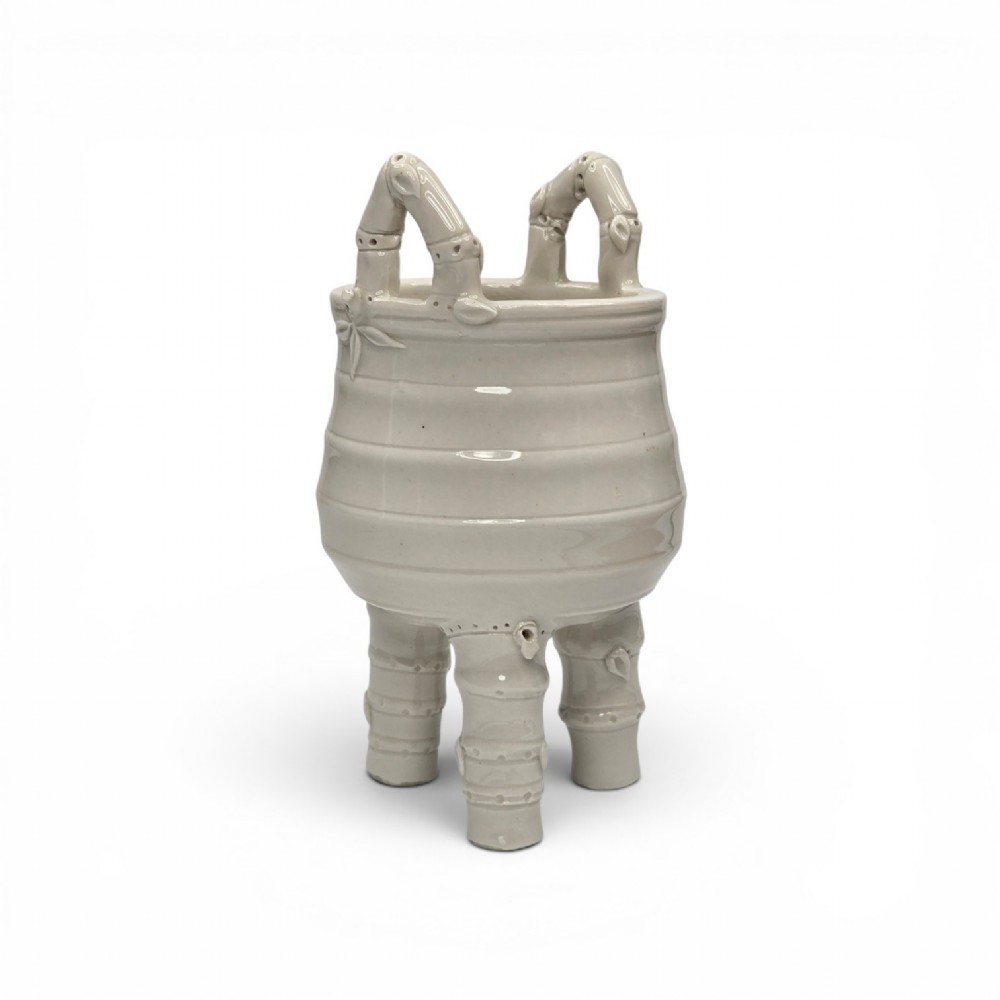 An off-white porcelain tripod censer featuring bamboo-node shaped legs, elevated loop handles, and subtle horizontal ridges across the body.