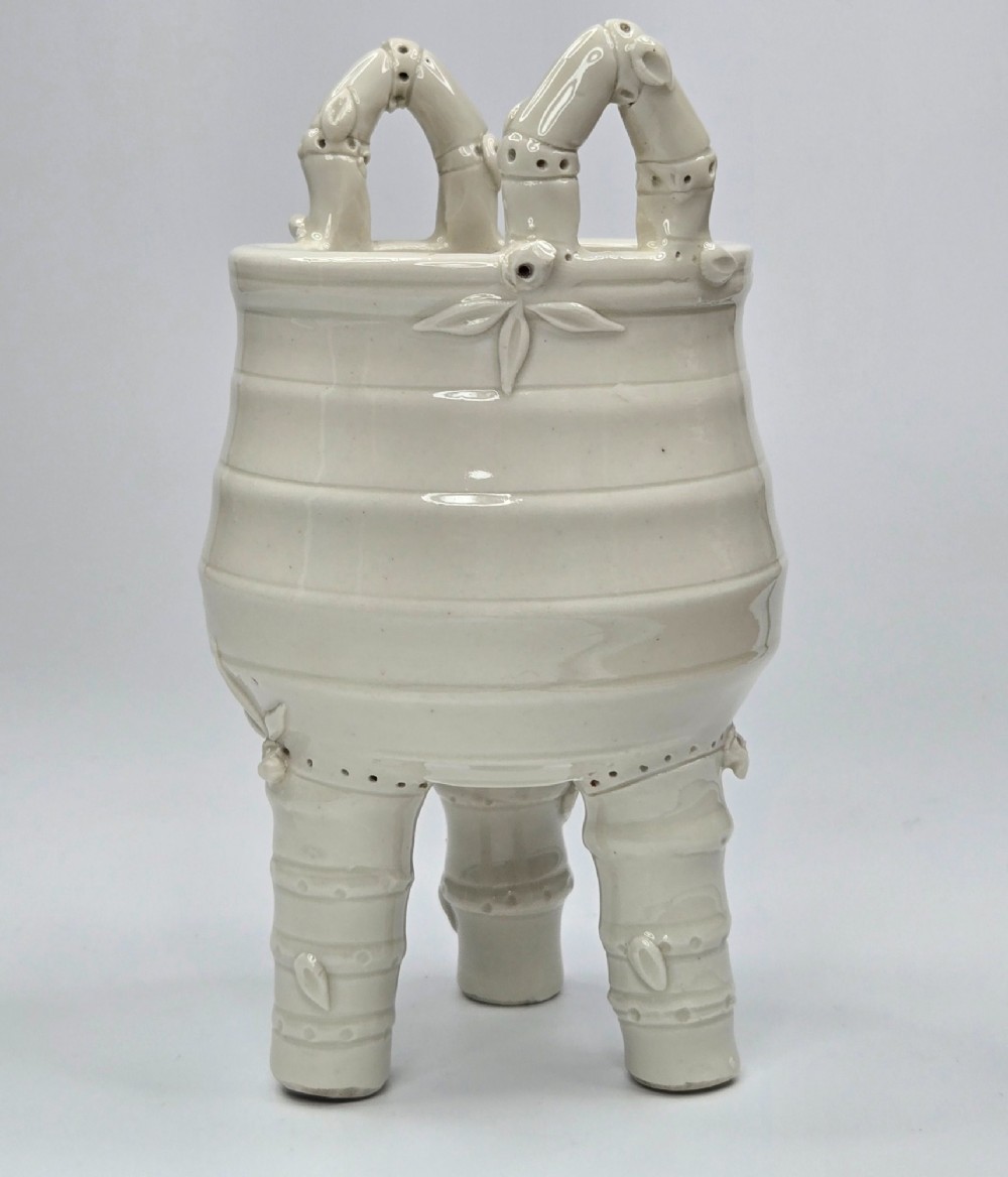 An off-white porcelain tripod censer featuring bamboo-node shaped legs, elevated loop handles, and subtle horizontal ridges across the body. View III