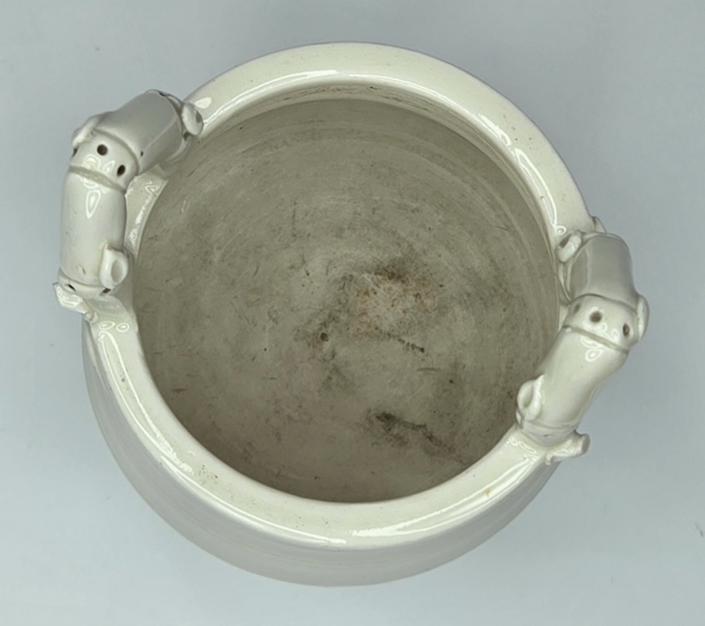 An off-white porcelain tripod censer featuring bamboo-node shaped legs, elevated loop handles, and subtle horizontal ridges across the body. View V