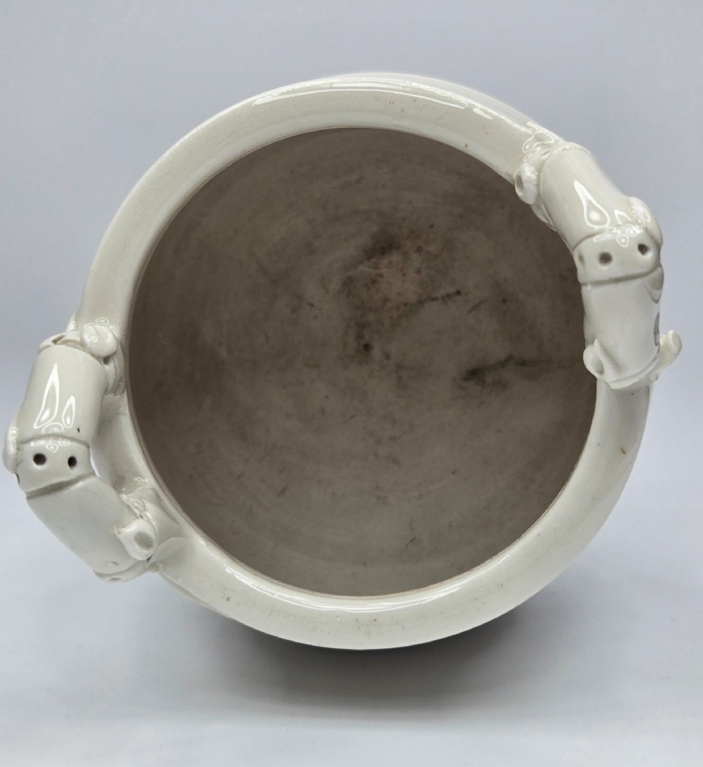 An off-white porcelain tripod censer featuring bamboo-node shaped legs, elevated loop handles, and subtle horizontal ridges across the body. View VI
