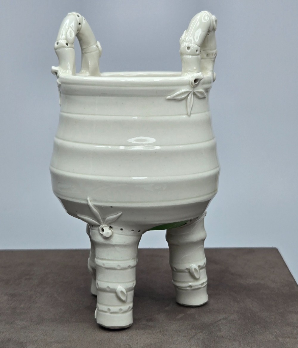 An off-white porcelain tripod censer featuring bamboo-node shaped legs, elevated loop handles, and subtle horizontal ridges across the body. View XI