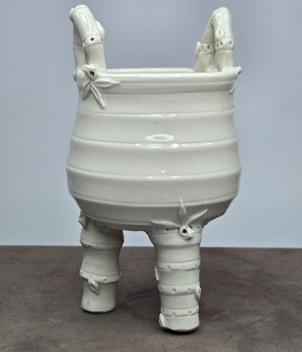 An off-white porcelain tripod censer featuring bamboo-node shaped legs, elevated loop handles, and subtle horizontal ridges across the body. View XII