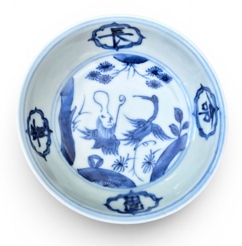 A circular Chinese blue and white porcelain deep saucer dish decorated with cobalt underglaze imagery of Shoulao, a crane, and character cartouches.