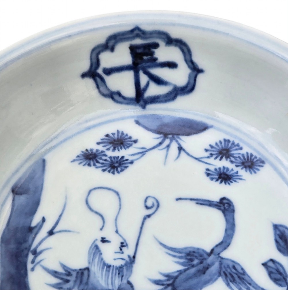 A circular Chinese blue and white porcelain deep saucer dish decorated with cobalt underglaze imagery of Shoulao, a crane, and character cartouches. View V
