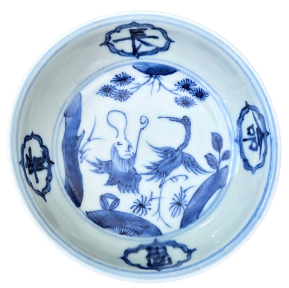 A circular Chinese blue and white porcelain deep saucer dish decorated with cobalt underglaze imagery of Shoulao, a crane, and character cartouches. View VI