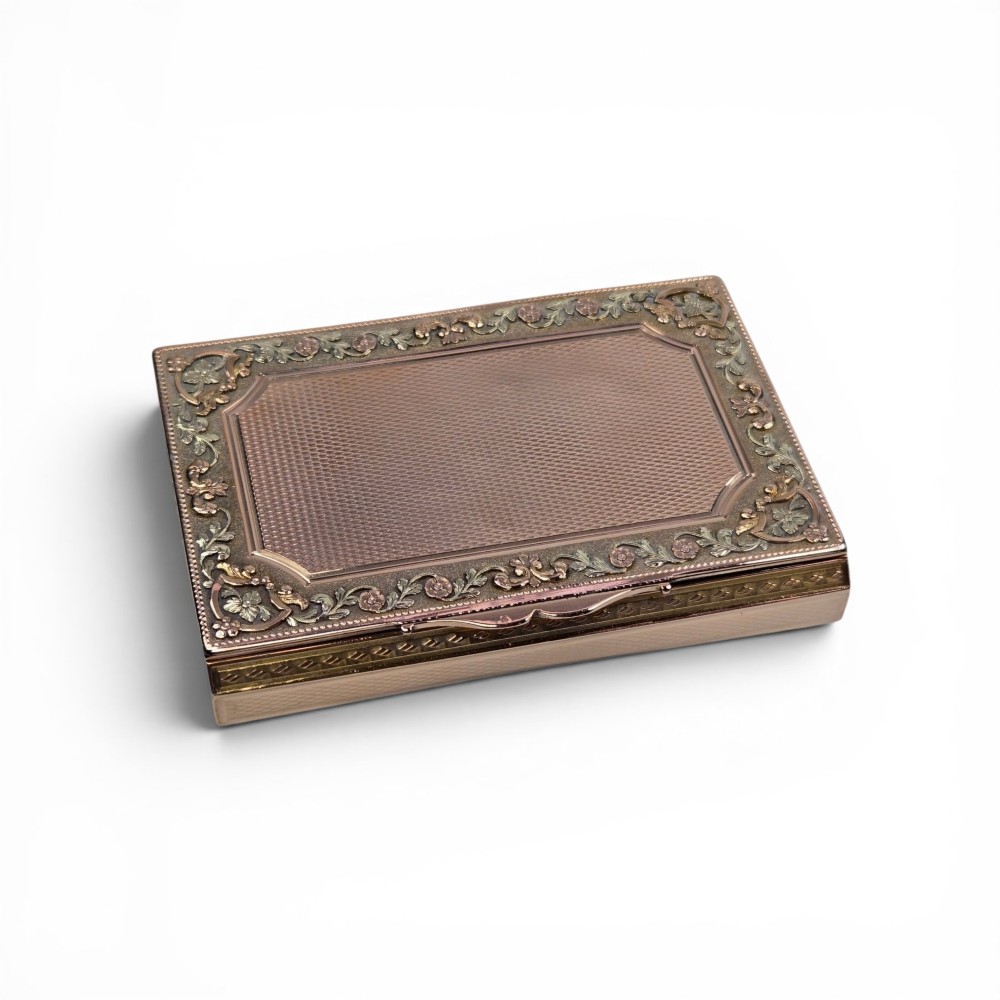 A rectangular 18K gold snuff box featuring engine-turned panels and chased floral relief borders in multi-toned gold.