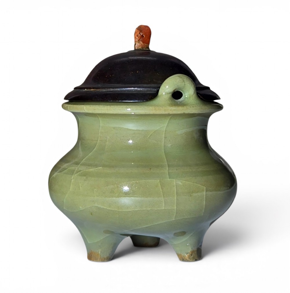 A miniature pale celadon green tripod censer with a distinct crackle glaze, fitted with a dark wood cover and a carved red coral finial.