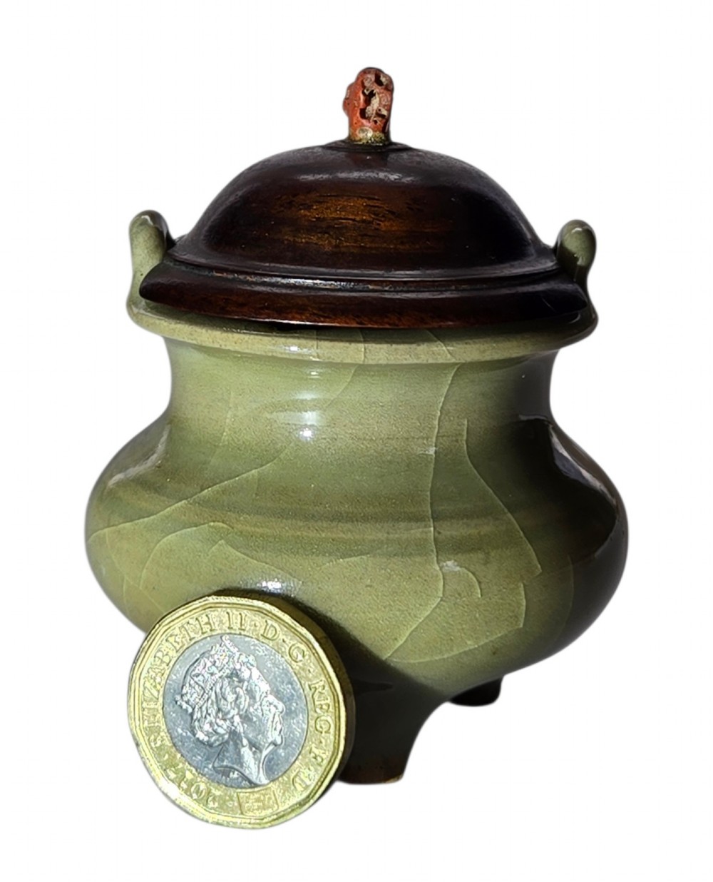 A miniature pale celadon green tripod censer with a distinct crackle glaze, fitted with a dark wood cover and a carved red coral finial. View V