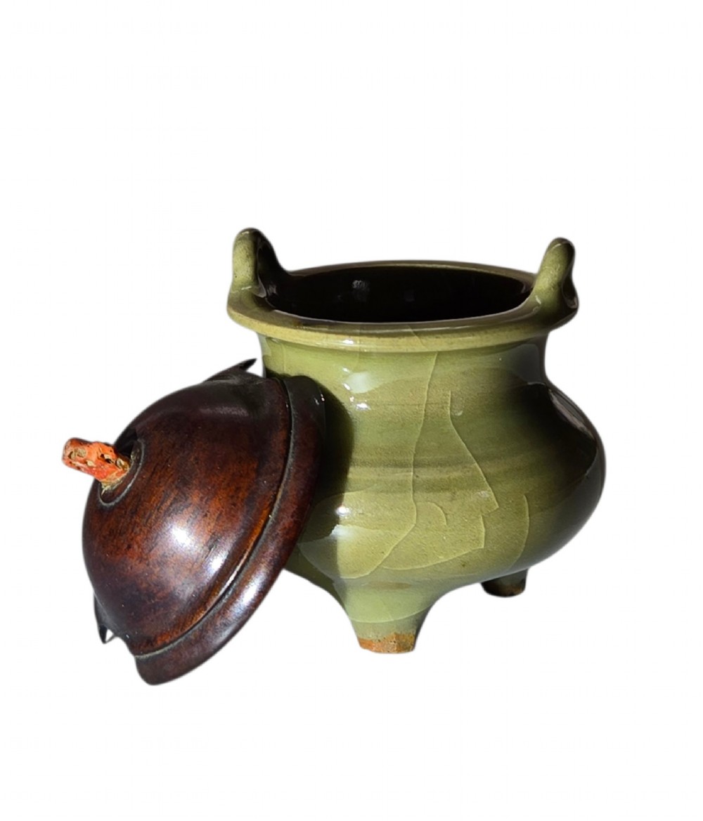 A miniature pale celadon green tripod censer with a distinct crackle glaze, fitted with a dark wood cover and a carved red coral finial. View IX