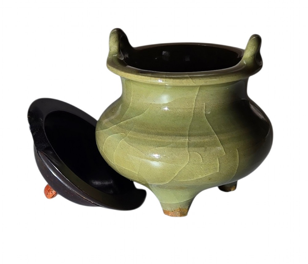 A miniature pale celadon green tripod censer with a distinct crackle glaze, fitted with a dark wood cover and a carved red coral finial. View X