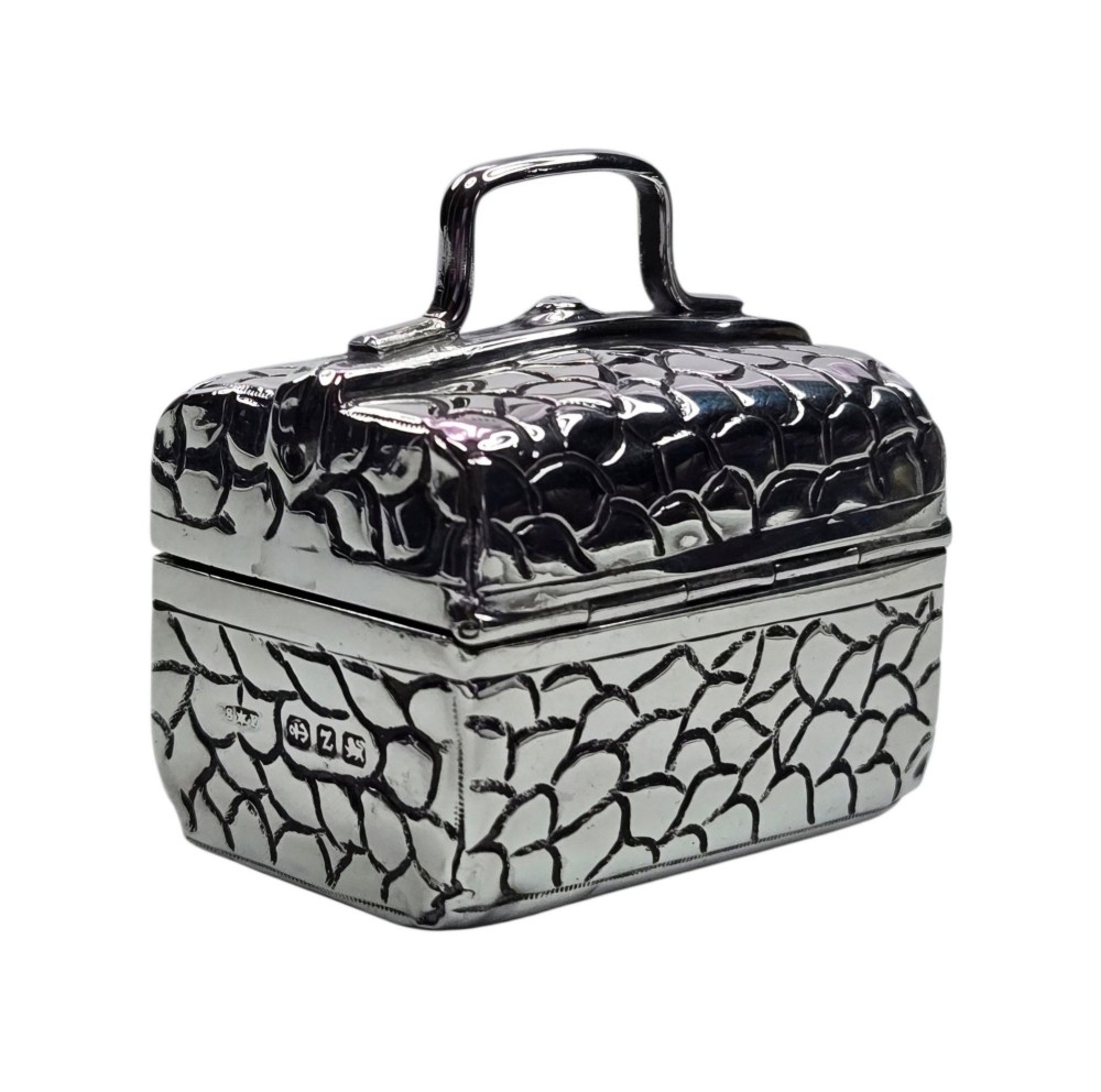 A late Victorian sterling silver novelty box crafted in the form of a miniature trunk with embossed crocodile skin texture and a top carrying handle. View II