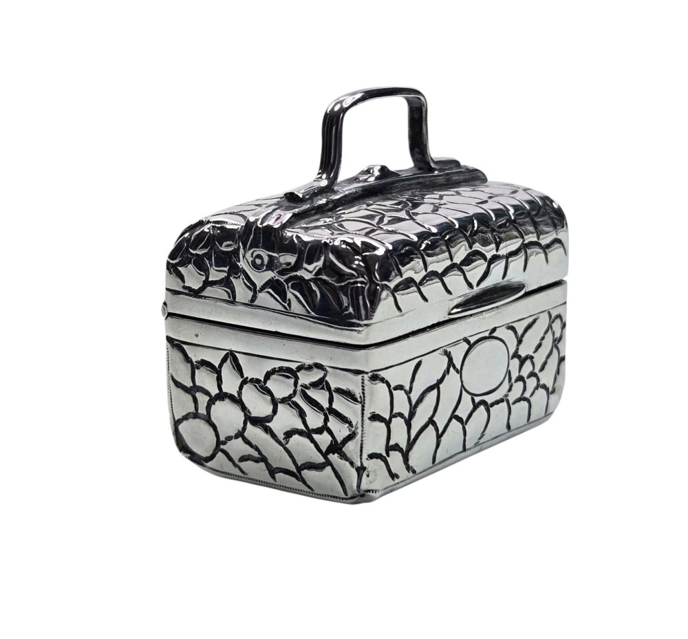 A late Victorian sterling silver novelty box crafted in the form of a miniature trunk with embossed crocodile skin texture and a top carrying handle. View V