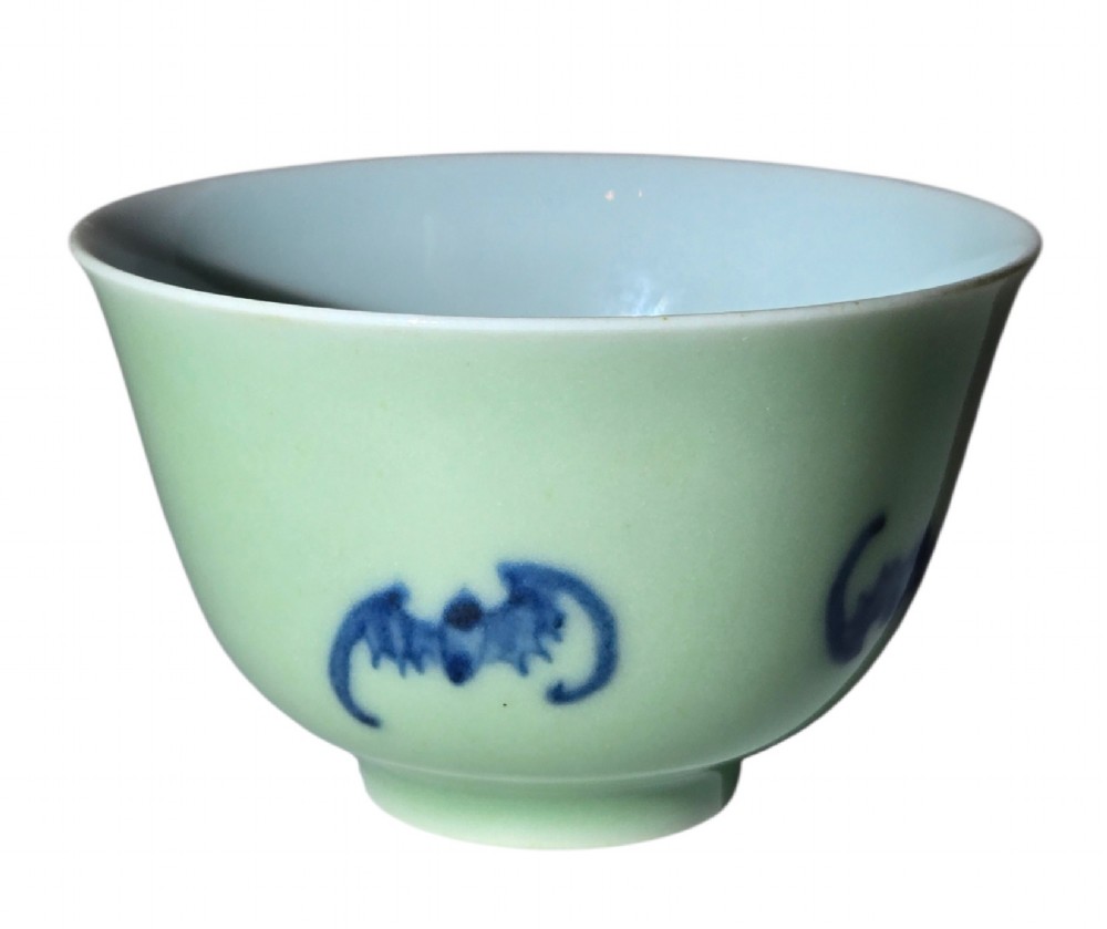A small Chinese celadon green glazed porcelain cup decorated with underglaze blue bat motifs around the exterior. View V