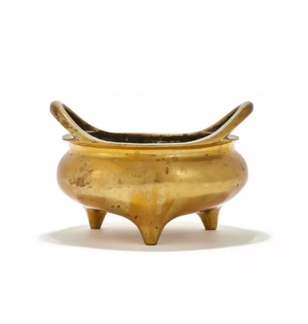 A heavy cast golden brass tripod censer featuring loop handles and three tapered feet.
