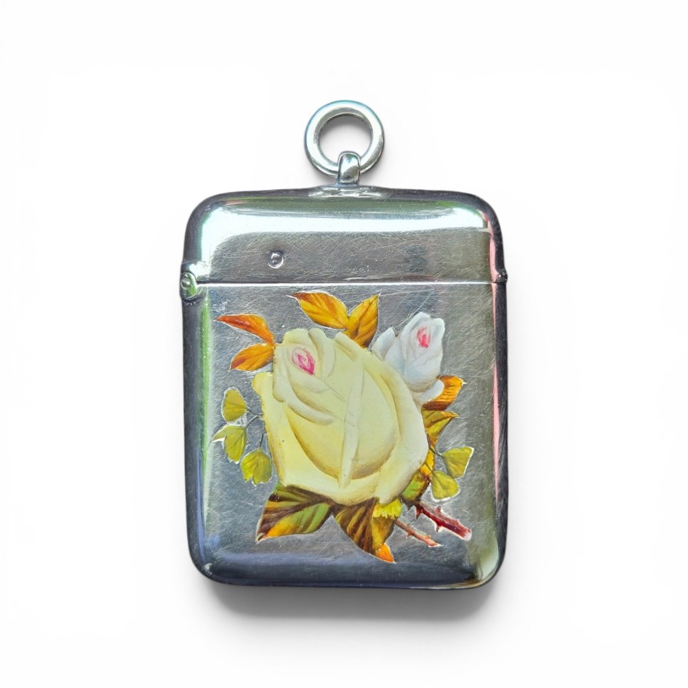 A rectangular sterling silver vesta case featuring hand-painted yellow and white roses in enamel with a top suspension loop. View II