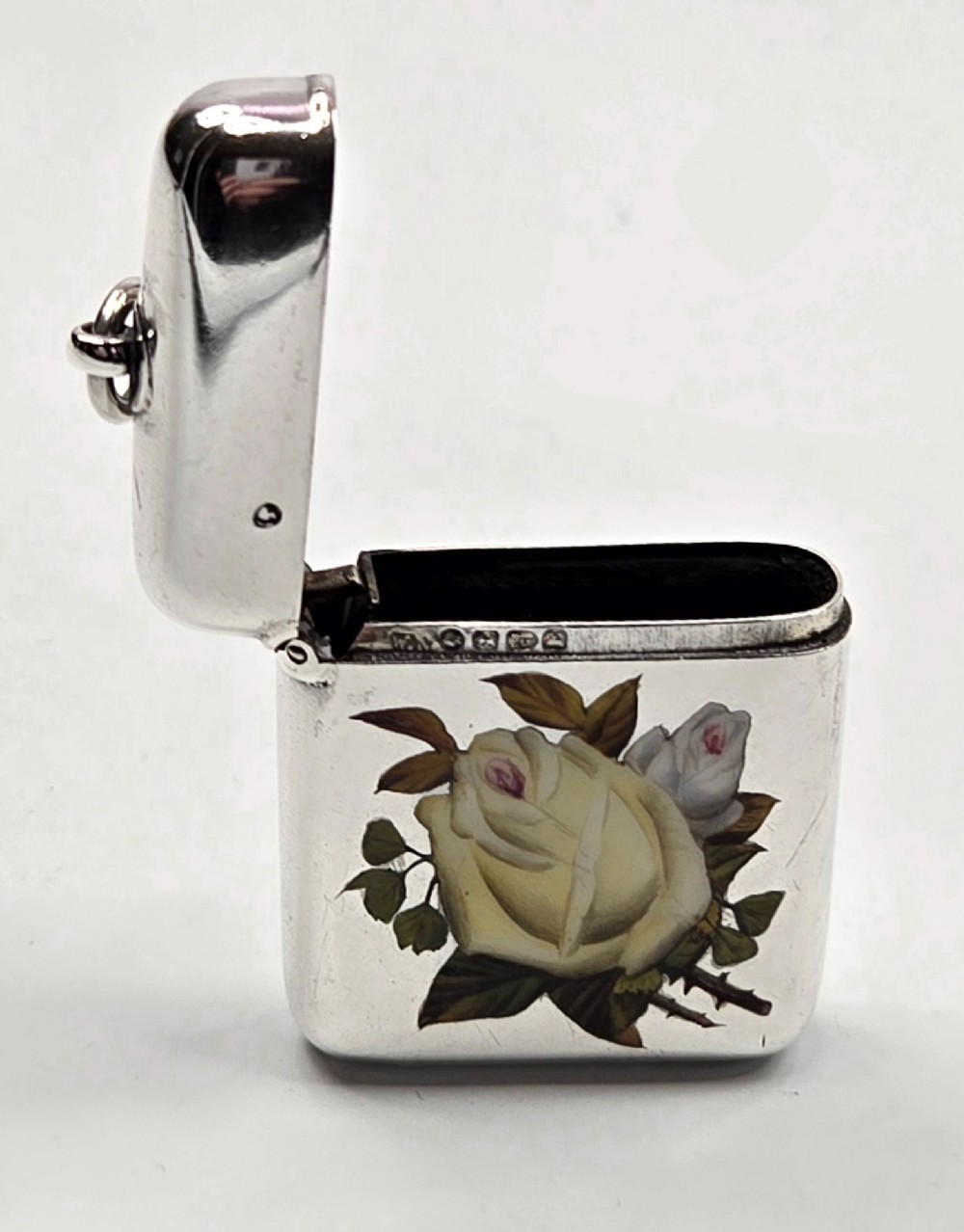 A rectangular sterling silver vesta case featuring hand-painted yellow and white roses in enamel with a top suspension loop. View IV