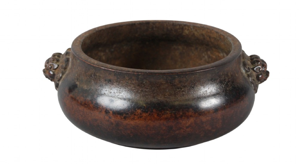 A heavy dark brown cast bronze incense burner featuring a low compressed circular form decorated with relief beast mask handles. View IV