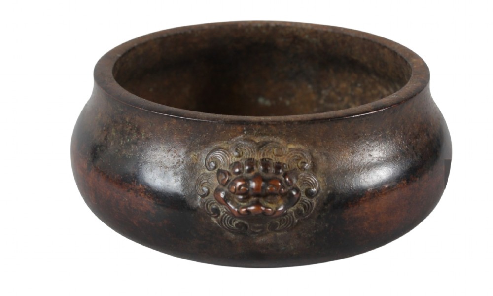 A heavy dark brown cast bronze incense burner featuring a low compressed circular form decorated with relief beast mask handles. View VII